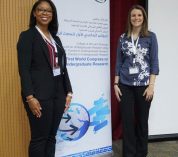Aleah Dungee and Kathryn Bloodworth stand by a poster at a professional conference.