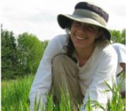 Emily Grman smiles while crouching in a field.
