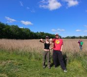 Two undergraduate researchers stand at the edge of a wheat field at the Kellogg Biological Station.