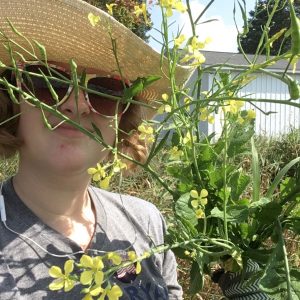 Ava Garrison poses for a photo with an uprooted weedy radish plant.