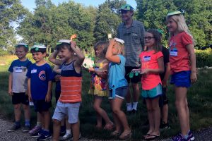 Intern Blake Hedges stands with a group of children showing off the turtle crafts they created.