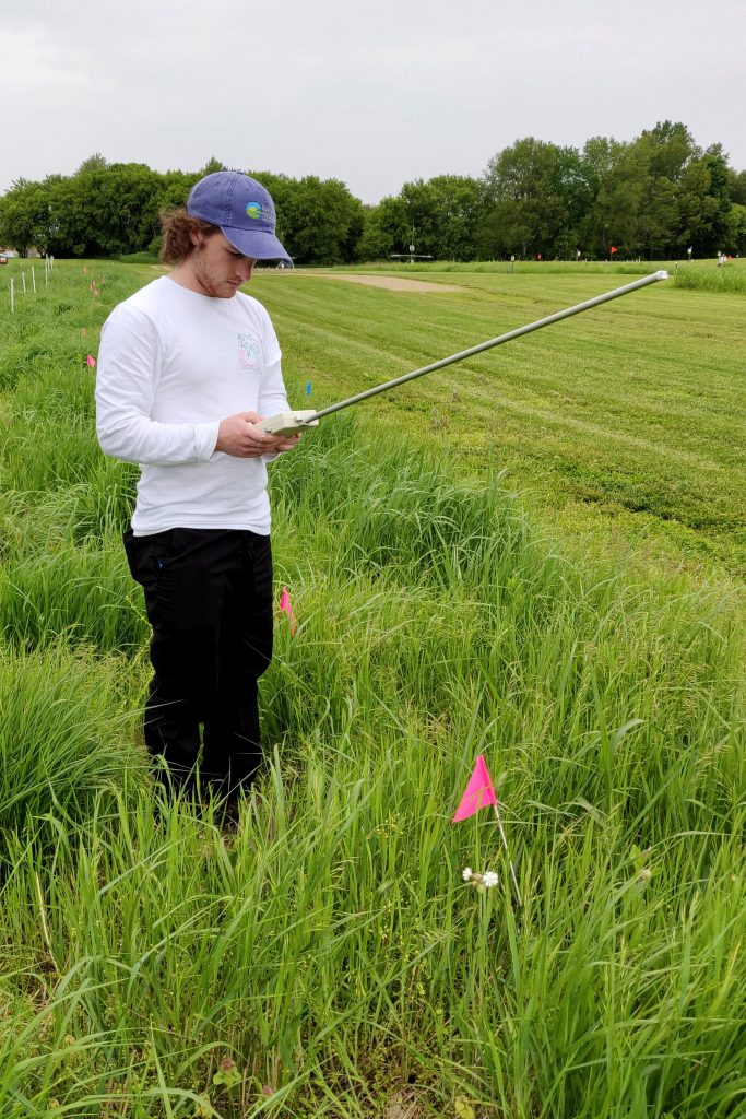 Colin McHugh stands in a research field at the Kellogg Biological Station.