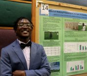 Jabarius Jones smiles while standing next to his project poster.