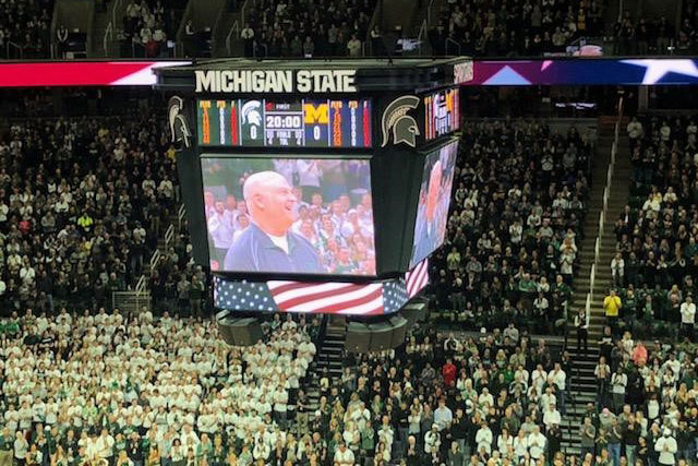 The jumbotron at MSU's Breslin Center shows a smiling Jim Allen, who was being recognized for his military service.