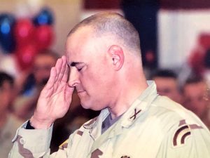 Jim Allen renders a military salute, with eyes closed, wearing tan fatigues, upon return from a tour in Iraq.