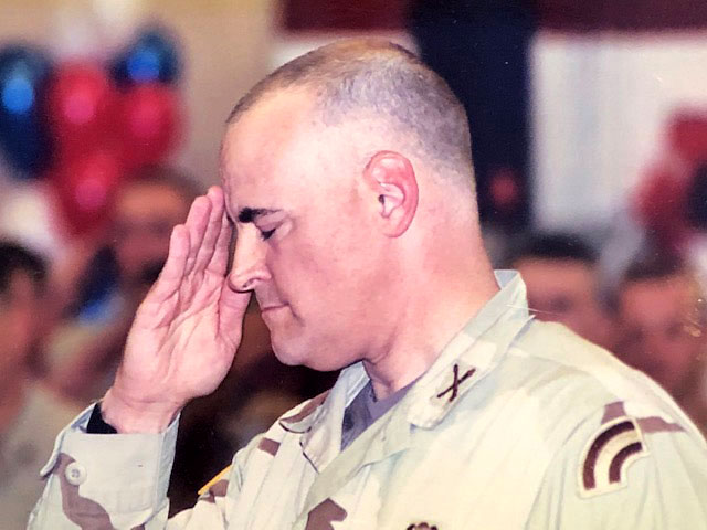 Jim Allen renders a military salute, with eyes closed, wearing tan fatigues, upon return from a tour in Iraq.