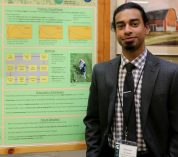 Brandon D'Souza stands next to his research poster.