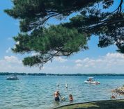 A man plays in the shallows of Gull Lake off of Windmill Island with young children. Photo credit: Maria Newhouse Photography.