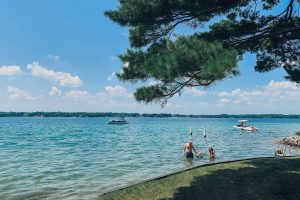 A man plays in the shallows of Gull Lake off of Windmill Island with young children. Photo credit: Maria Newhouse Photography.