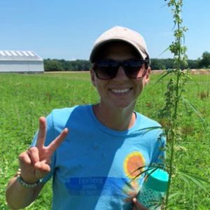 Alyssa Schuck makes a peace sign while standing in a field at Kellogg Farm.