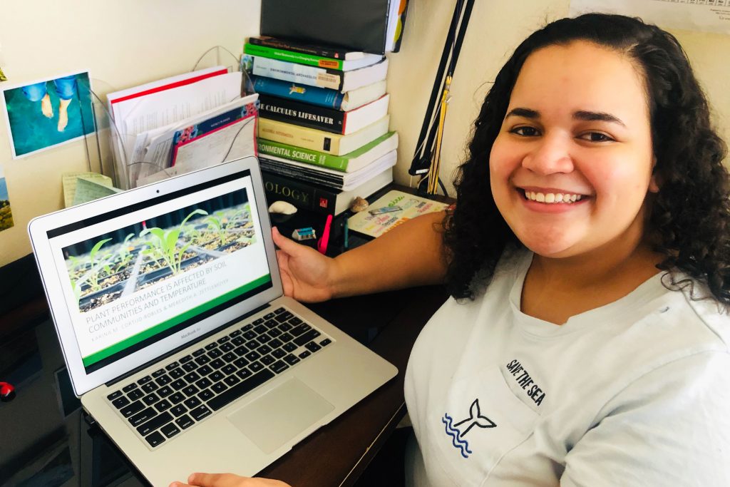 Karina Cortijo-Robles smiles while sitting at a desk with a laptop computer.