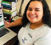 Karina Cortijo-Robles smiles while sitting at a desk with a laptop computer.