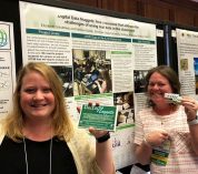 From left, Melissa Kjelvik and Elizabeth Schultheis stand in front of a poster presentation for Data Nuggets.