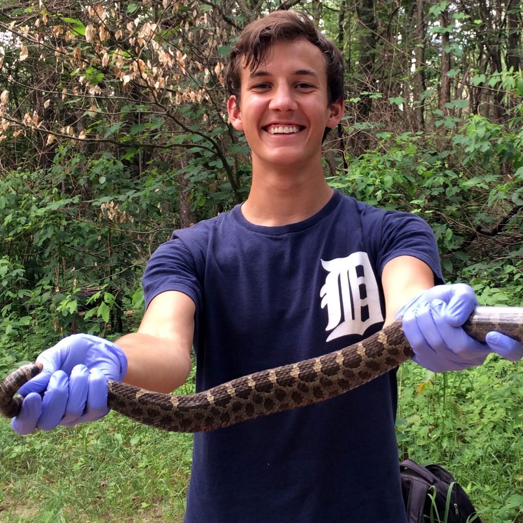 Caleb Krueger smiles while holding a large snake.