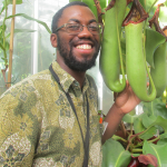 Kadeem Gilbert poses next to a large carnivorous plant.