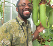 Kadeem Gilbert poses next to a large carnivorous plant.