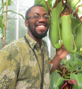 Kadeem Gilbert poses next to a large carnivorous plant.