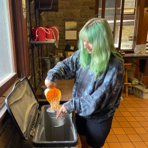 Cheyenne Cope scoops corn into a small bucket inside the W.K. Kellogg Bird Sanctuary's Resource Center.