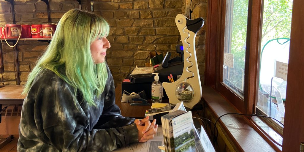 Cheyenne Cope sits at a desk inside the W.K. Kellogg Bird Sanctuary, looking out the window that visitors use to pay admission.