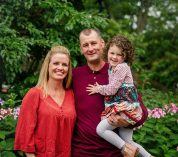 A family poses for photos outside the W.K. Kellogg Manor House with autumn gardens in the background.