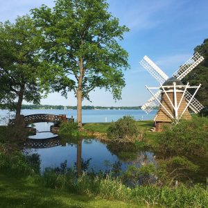 A summer view of KBS's Windmill Island, showing the island's windmill and footbridge, with Gull Lake in the background.