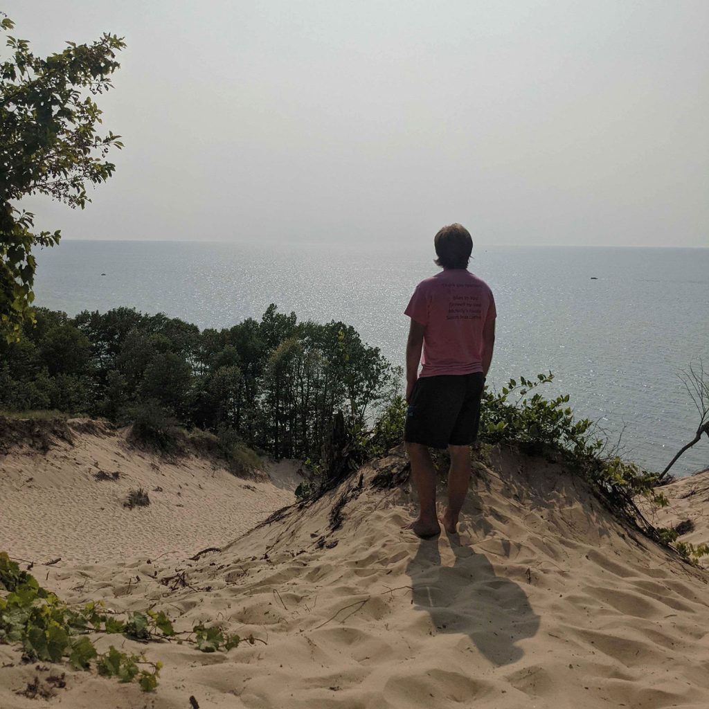 Bjorn Larson stands on a sand dune, looking out over Lake Michigan at Van Buren State Park