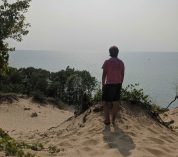 Bjorn Larson stands on a sand dune, looking out over Lake Michigan at Van Buren State Park