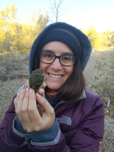 Elizeth Cinto Mejia outdoors with a ruby crowned kinglet in her hands