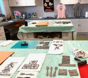 Supplies used for block print projects along with some finished items lie on a table.