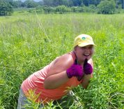 Sarah Johnson gives a thumbs-up while working in a prairie restoration plot at Kellogg Biological Station.