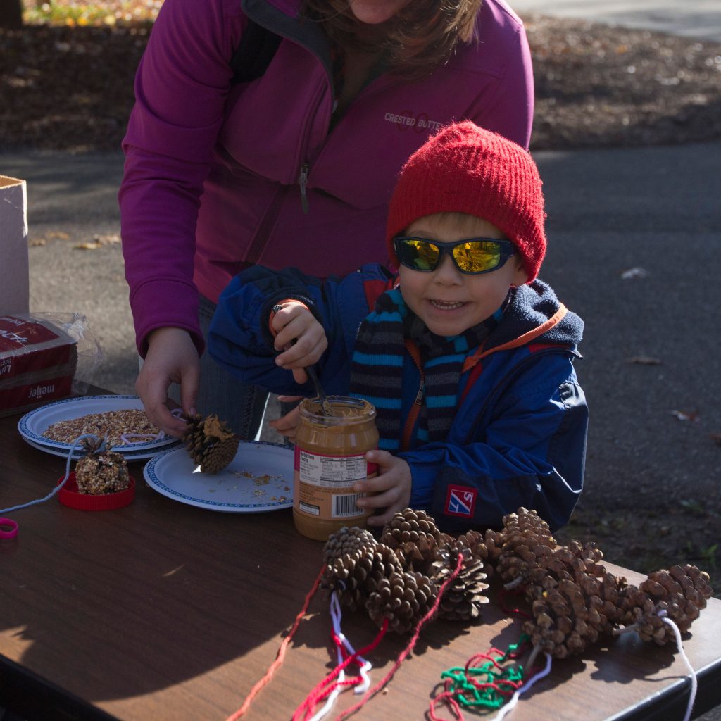 A small child scoops peanut butter in a bird feeder-making activity at Wild Wednesdays.
