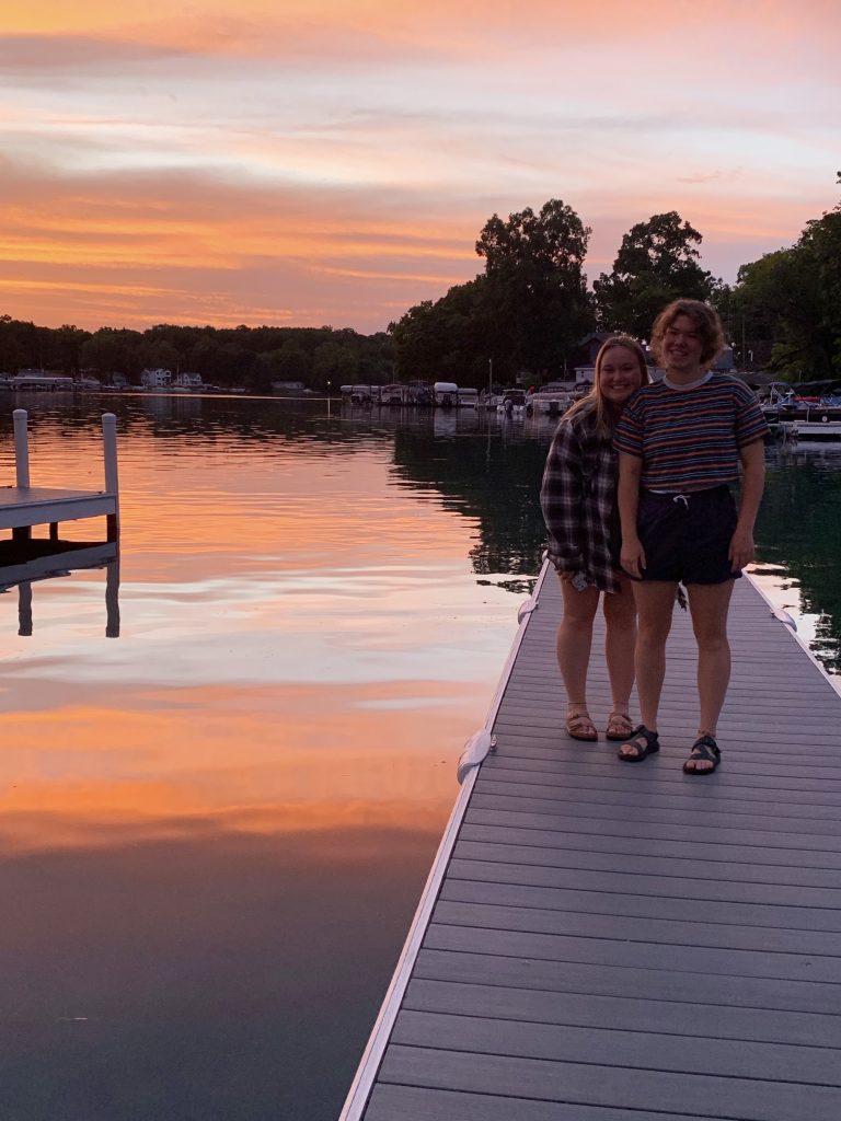 Alex Sills stands with a fellow KBS summer student on a dock on Gull Lake at sunset.