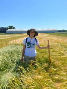 Sarah Hubbard stands in a wheat field against a blue sky at the W.K. Kellogg Farm.