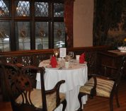 A table for two with a white tablecloth, set for dinner, overlooks a window at the W.K. Kellogg Manor House.