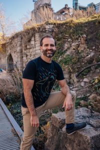 Matt Wilkins standing in front of a plant covered rock wall