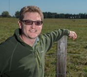 Dr. Jason Rowntree leans on a fence post in front of a pasture.