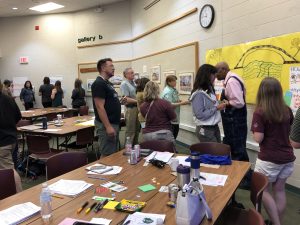 Educators use markers and sticky notes to add ideas to a poster, hanging on the wall of the auditorium at the W.K. Kellogg Biological Station.