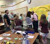 Educators use markers and sticky notes to add ideas to a poster, hanging on the wall of the auditorium at the W.K. Kellogg Biological Station.