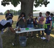 teachers looking in microscopes at seeds under the shade of an oak tree