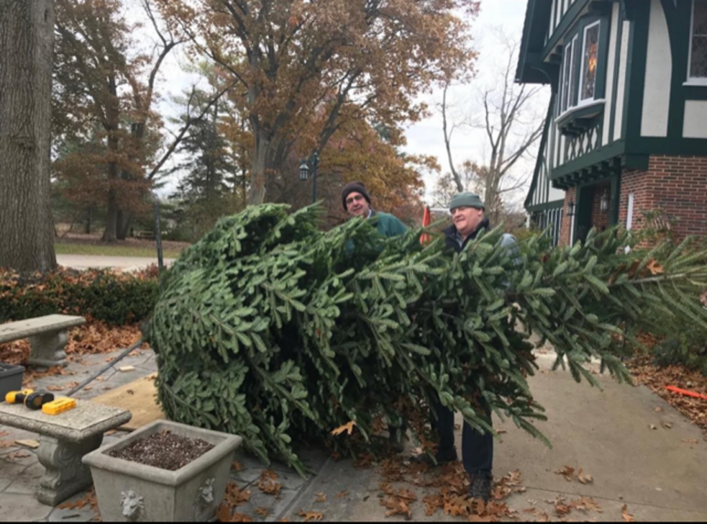 Jim Allen and Stu Bassett help install a Christmas tree outside the Kellogg Manor House.