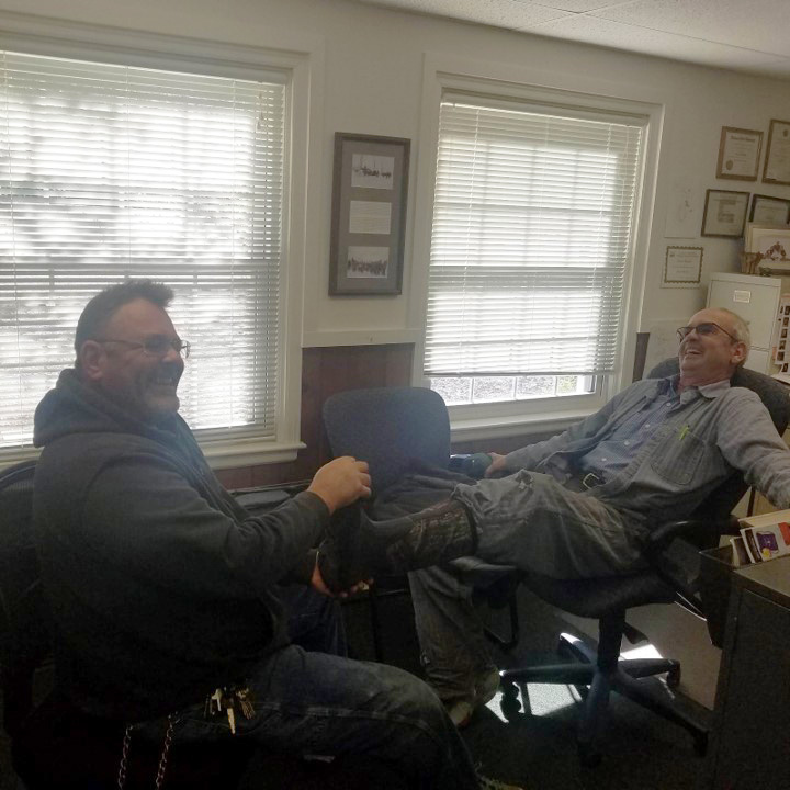 Stu Bassett and a colleague laugh together in Stu's office.