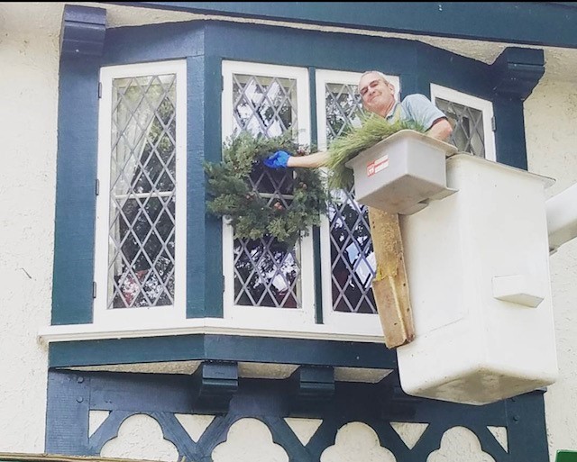 Stu Bassett hands a wreath on a second-floor window at the Kellogg Manor House.