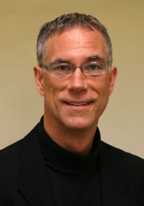 headshot of Dr. Allen Webb smiling in a black turtle neck shirt