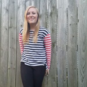 Hannah Fisher stands in front of a tall privacy fence.