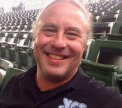 Photo of a smiling Andy Fogiel, seated in in a ballpark.