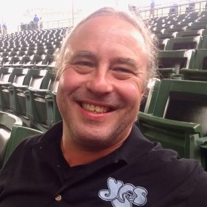 Photo of a smiling Andy Fogiel, seated in in a ballpark.