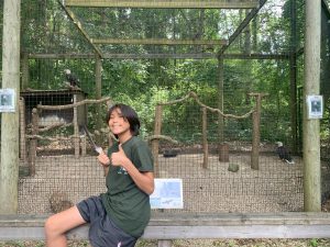Student Cassius Caldwell, holds an eagle feather and gives a thumbs-up in front of the eagle enclosure at the W.K. Kellogg Bird Sanctuary.