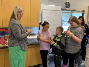 Students stand with Nicole Draft, founder of the More Love Collective, holding bracelets that they made as part of a lesson with her business.