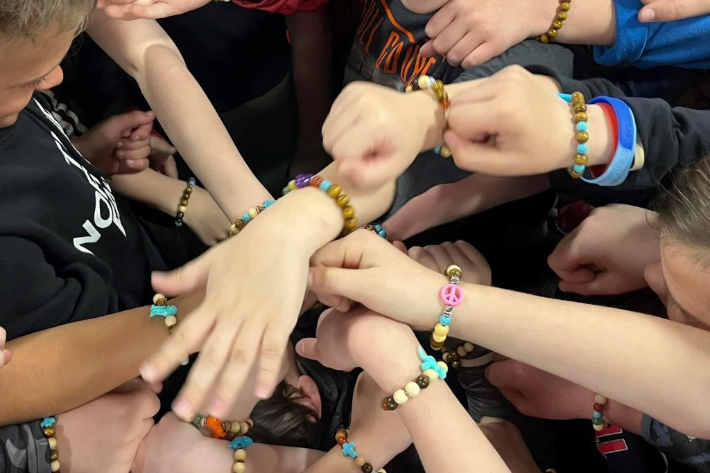 Close-up of several students holding out their arms to show off their bracelets.