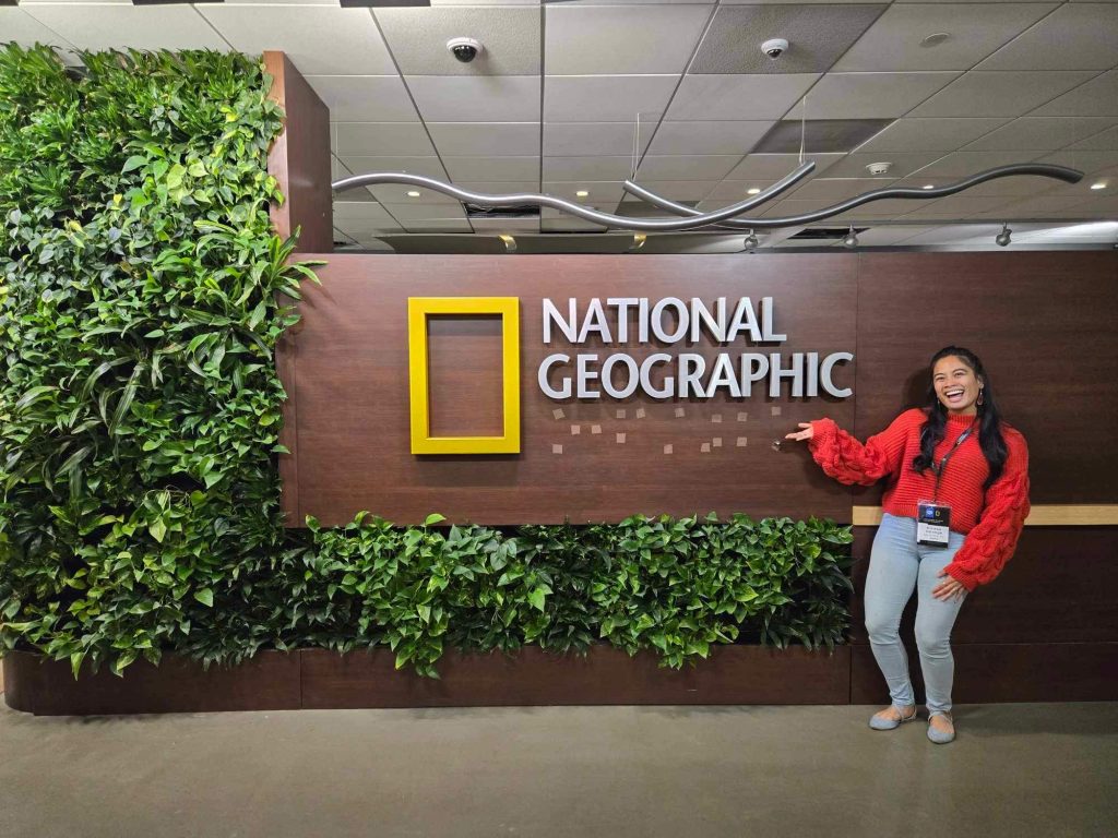 Educator Kirsten Salonga poses next to a National Geographic sign.